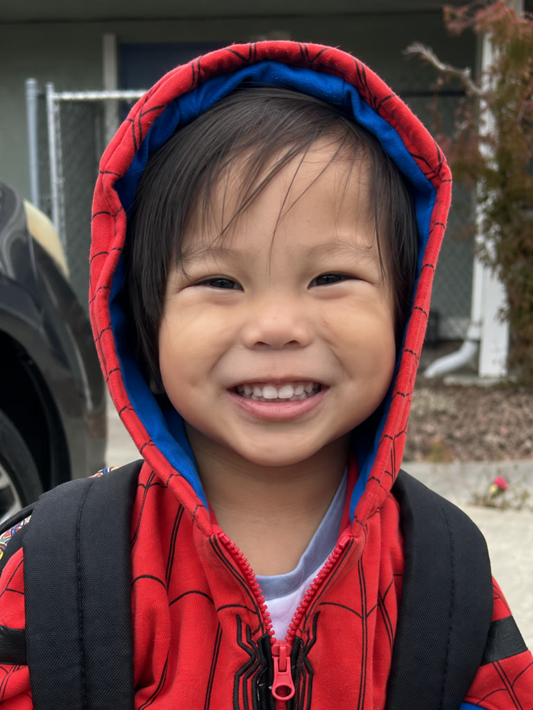 Kaius smiling in his red Spider-Man hoodie
